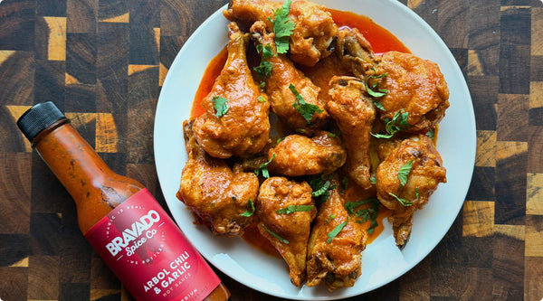 arbol chili and garlic hot sauce hot wings on plate next to hot sauce bottle