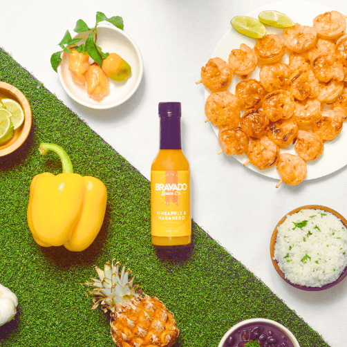 Pineapple and Habanero Hot Sauce surrounded by yellow belll pepper, habaneros and shrimp