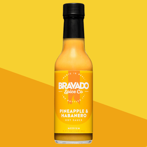 Bottle of Bravado Spice Co Pineapple & Habanero hot sauce on a yellow background